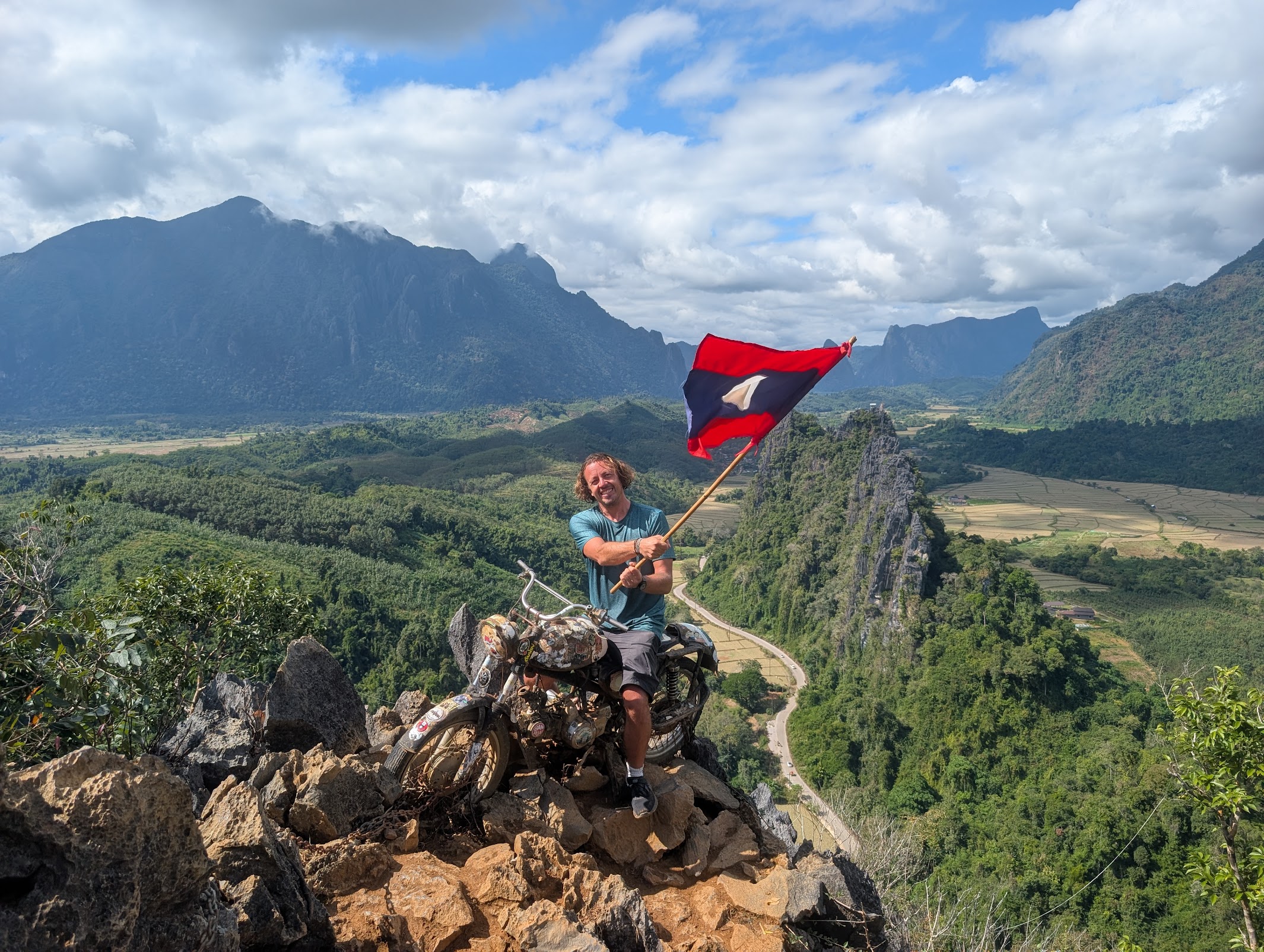 Ken with Laos flag on mountaintop